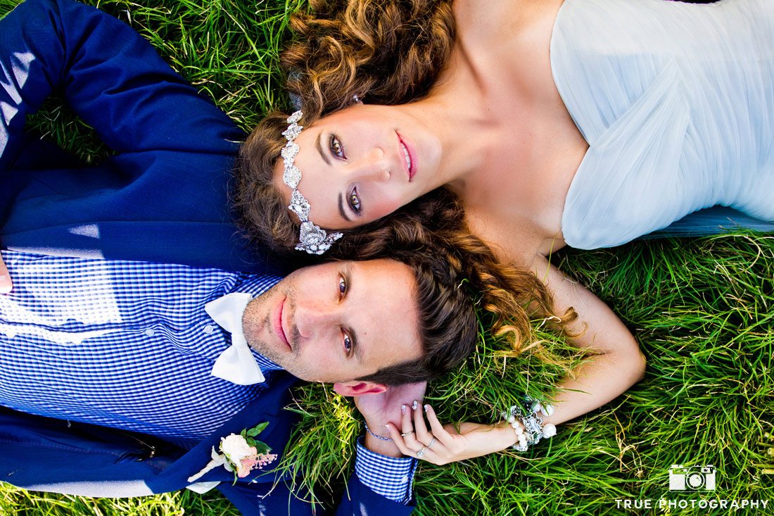 bride and groom lying on grass