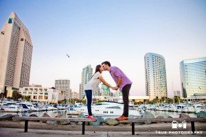 engaged couple on benches in front of harbor in San Diego
