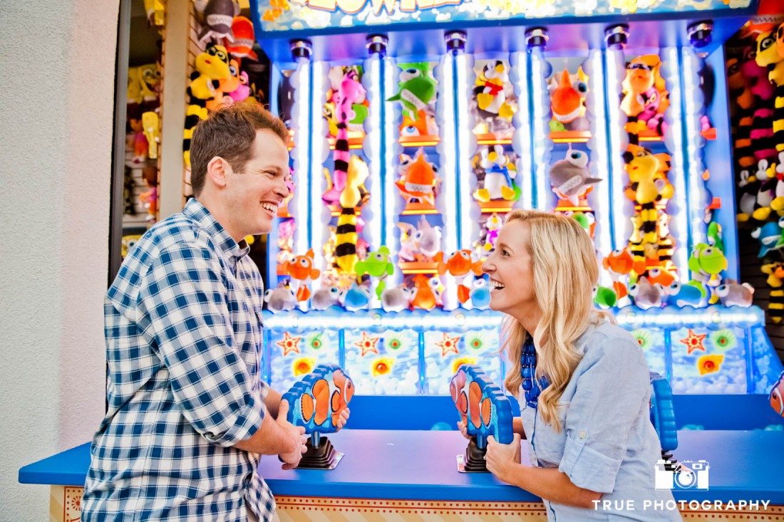 Engagement photo shoot of Mission Beach couple playing boardwalk game
