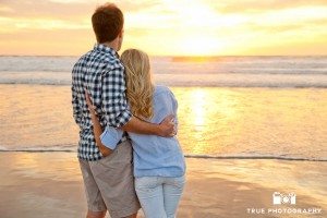 Engagement photo shoot of Mission Beach couple looking at waves