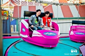 Engagement photo shoot of Mission Beach couple riding on purple carnival ride