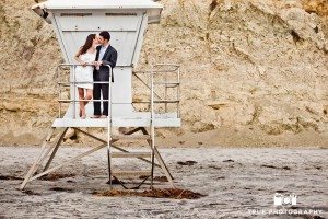 Engagement shoot of Del Mar Beach couple standing on lifeguard station