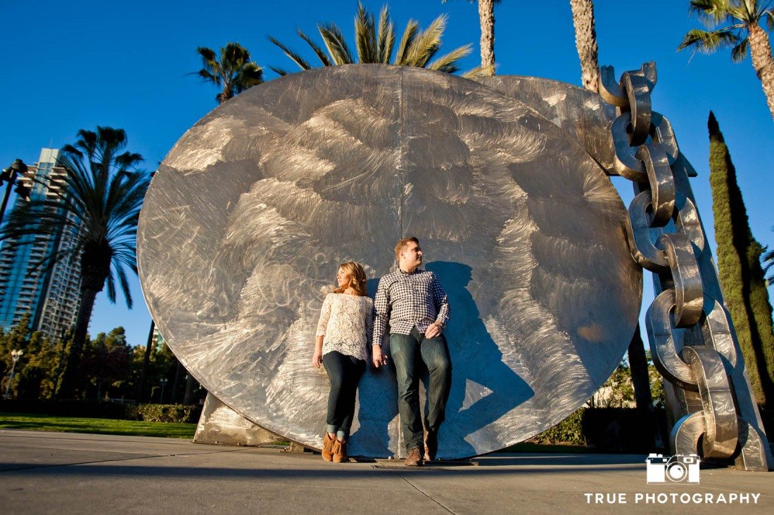 engaged couple and sculpture at downtown San Diego engagement photo shoot