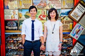 Engagement photo shoot of Mission Beach couple standing against t-shirt wall
