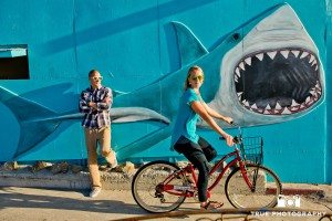 engagement photo shoot of Pacific Beach couple in front of shark picture