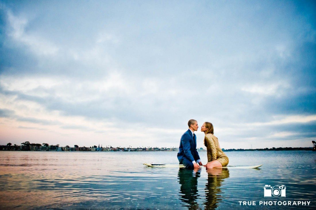 Engagement photo shoot of Pacific Beach clothed couple standing in the ocean