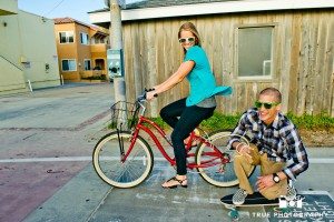 engagement photo shoot of Pacific Beach couple riding bike and skateboard