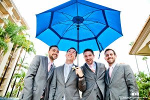 Groomsmen holding blue umbrella