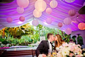 Couple kiss at sweetheart table during wedding reception