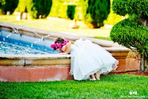 Flowergirl looks into fountain on wedding day