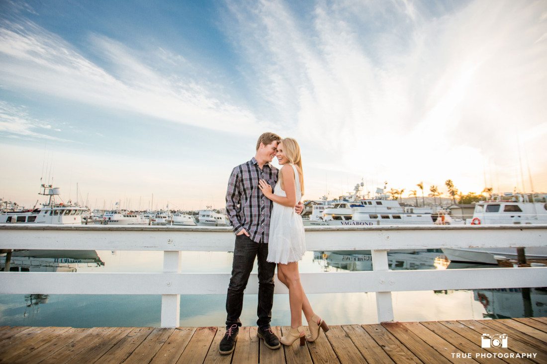 Colorful engagement photo of young vibrant couple on a dock in Point Loma, San Diego, California.