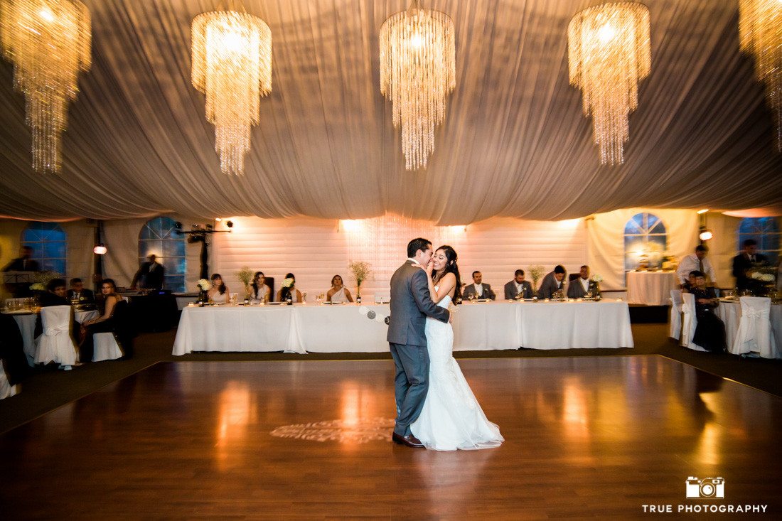 Couple share first dance together in tented pavilion during reception