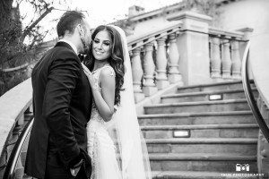 Intimate, black-and-white photo of bride and groom kissing on balcony at Grand Del Mar
