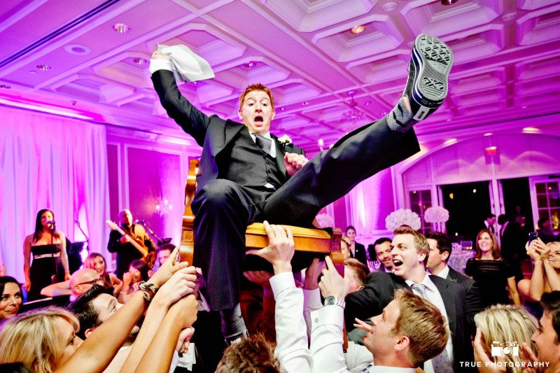 Groom is lifted in air by guests for hora dance