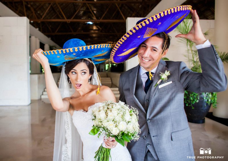 Newlyweds wearing blue sombreros in Mexico