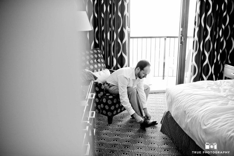 black-and-white photo of groom putting on shoes