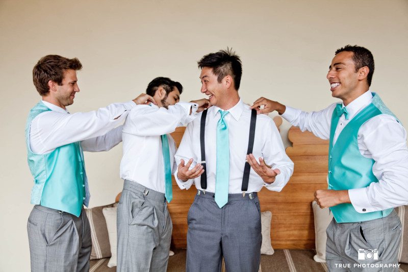 Groomsmen help the groom with his outfit