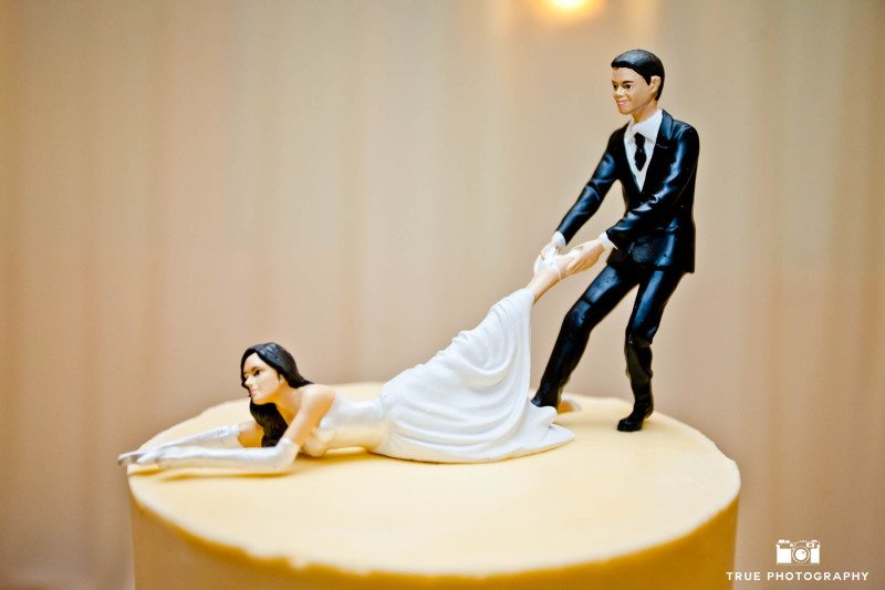 Funny cake topper with groom pulling bride