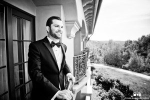 Groom on a balcony at the Fairmont Grand Del Mar wearing a classic black tuxedo