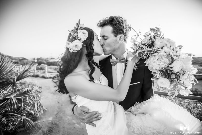 Newlyweds kissing on the bluffs of Carlsbad, California