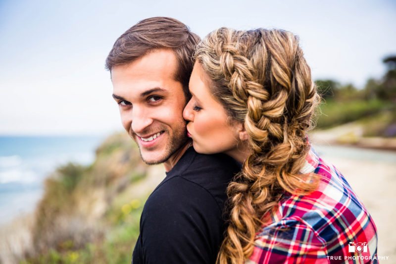 Girl kisses her fiance on the cheek during their engagement session.
