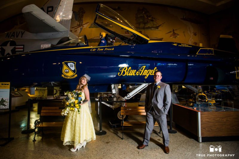 Bride and Groom stand in front of Blue Angels airplane at museum on wedding day