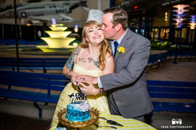 Groom kisses Bride as they cut wedding cake during reception