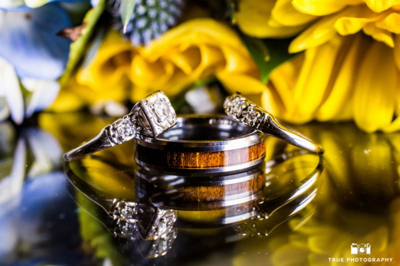 Wedding Rings in front of yellow and blue bouquet of flowers