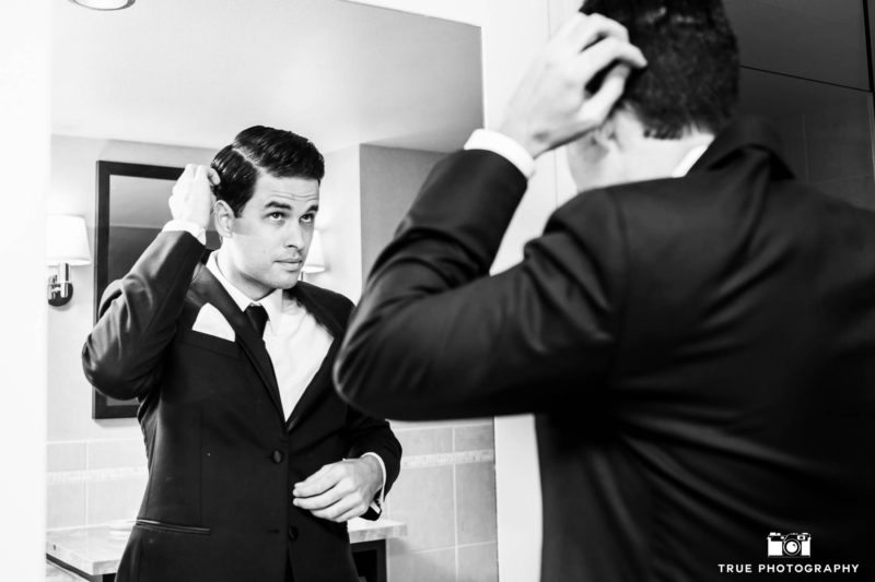 Modern groom looks in mirror and prepares for wedding day