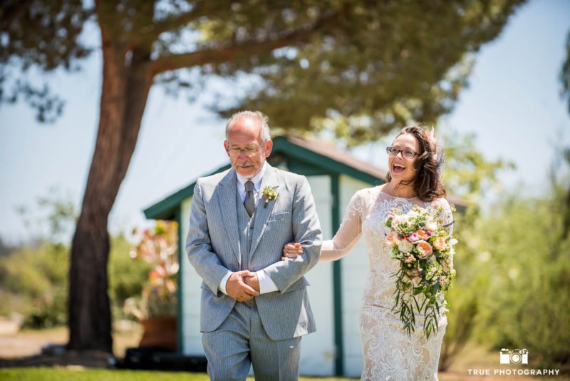 Bride and Father walk down aisle during outdoor rustic wedding in Vista
