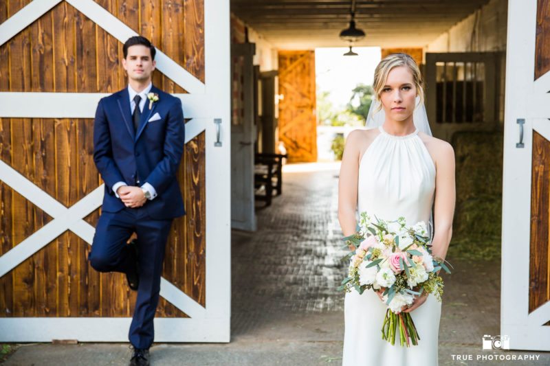Bride and Groom stand in front of rustic barn door after outdoor ceremony