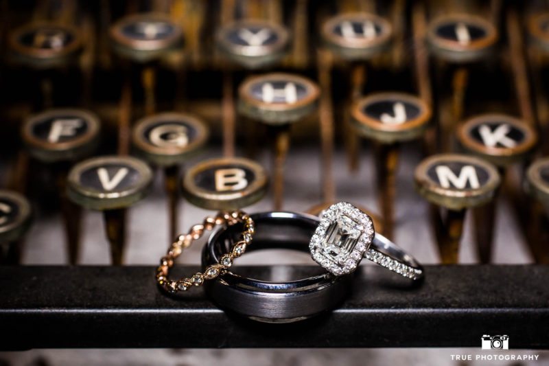 Bride and Groom's ornate diamond rings placed on vintage typewriter at rustic ranch wedding