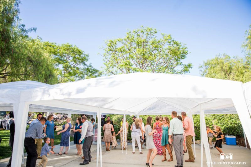 Wedding guests have fun dancing under tent at outdoor wedding reception