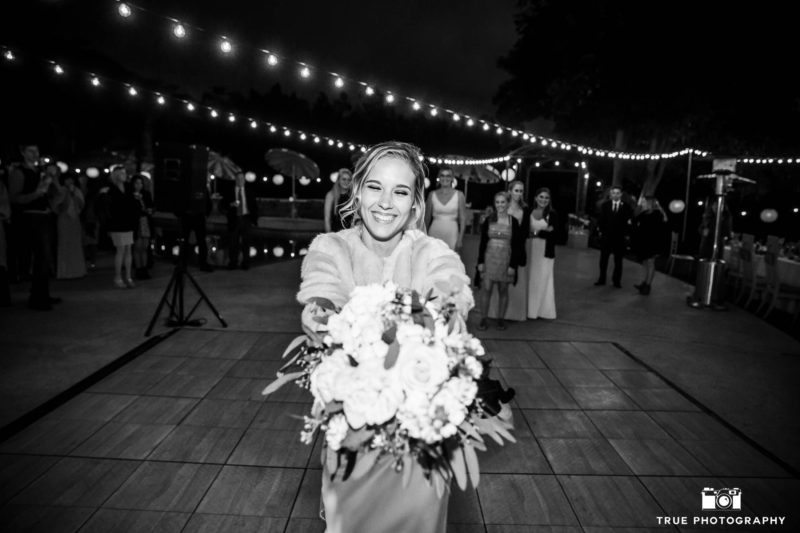 Bride prepares to toss bouquet during outdoor reception