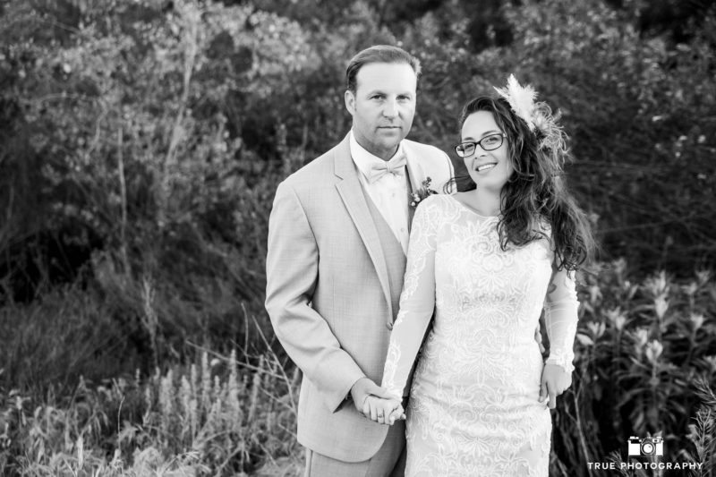 Black and White photo of Bride and Groom standing in grassy field on wedding day