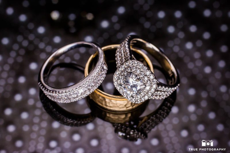 Bride's dazzling Halo wedding ring paired with eternity engagement band and groom's gold wedding band