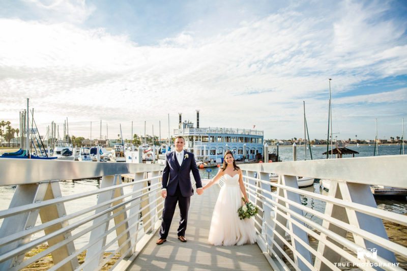 Bride and Groom hold hands on bridge at Bahia Resort