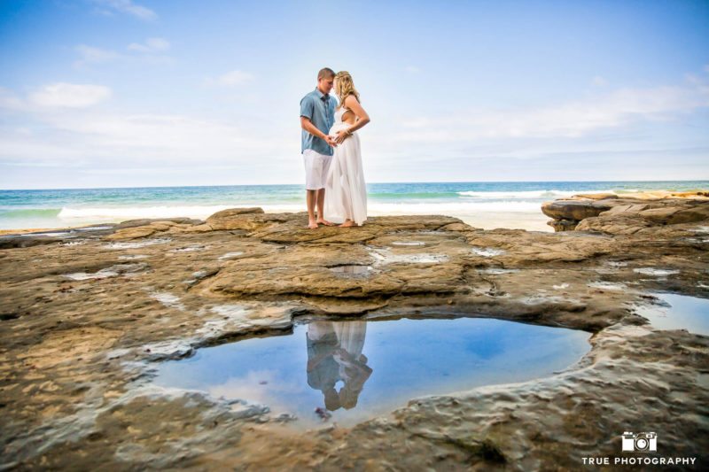 Expecting couple embraces during beach maternity
