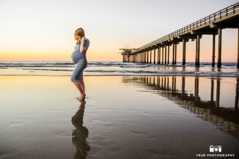 Expecting mother holds belly next to Scripps Pier