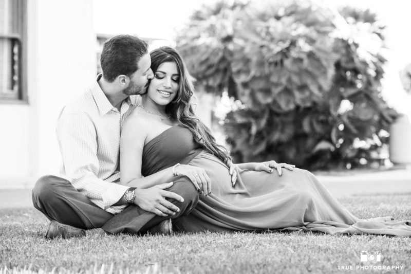 Expecting Couple sit on grass during maternity session