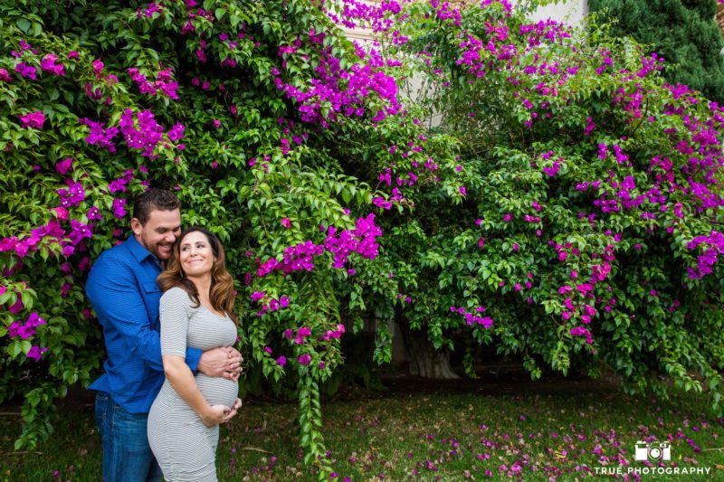 Husband and Wife embrace and laugh during cute maternity session