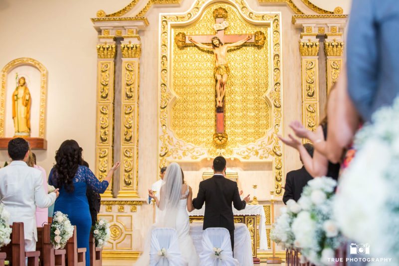 Bride and Groom receive blessing at front of altar during church ceremony