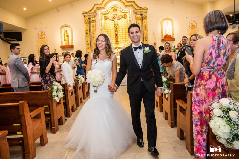 Bride and Groom's candid smiles as they walk down aisle after first kiss at Our Lady of Guadalupe church