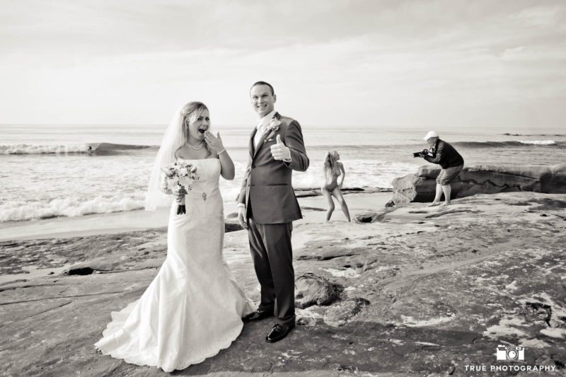 Bride and Groom make funny faces at beach as photographer take photos of model in background