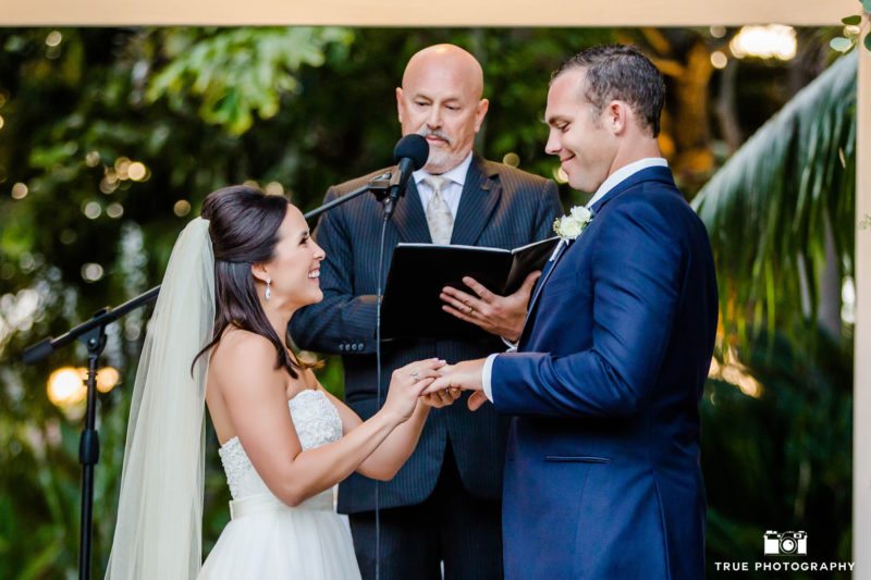 Bride places wedding ring on groom's hand
