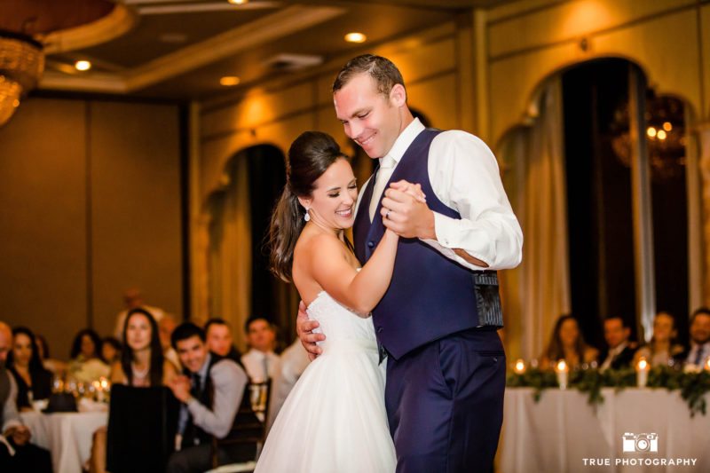 Grooms embraces Bride as they smile during First Dance