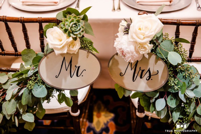 Mr. and Mrs. signs with flowers decorate sweetheart table chair
