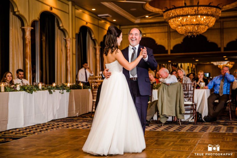 Father smiles while dancing during father and daughter dance at wedding reception