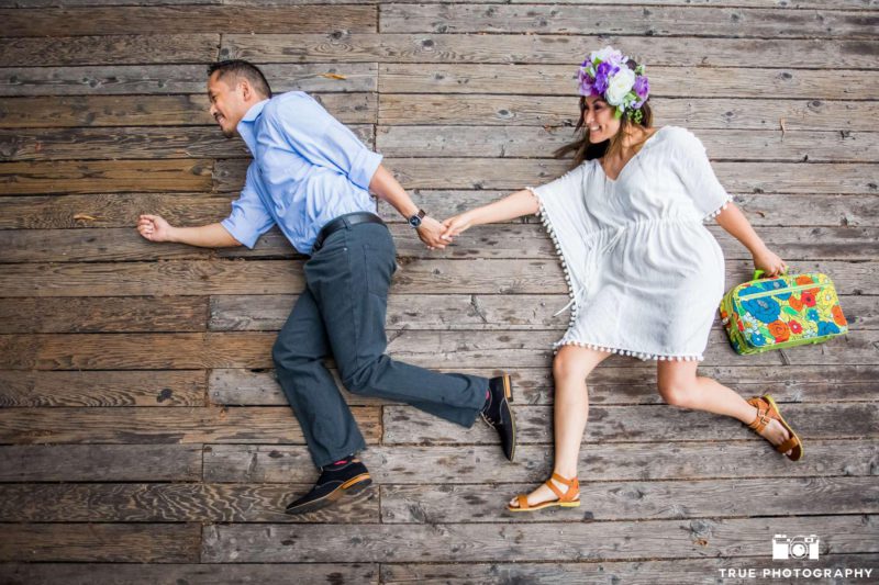 creative portrait of a couple on the ground with flower crown and suitcase