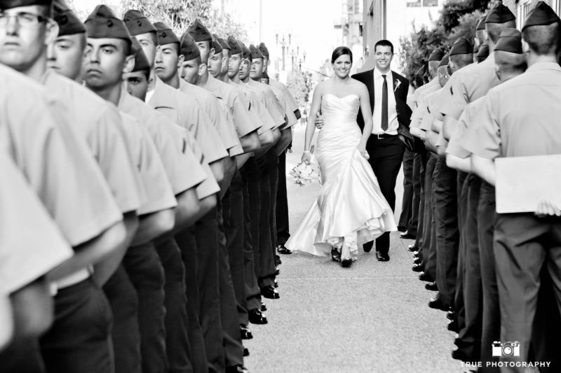 Bride and Groom smile and walk through row of armed service military men